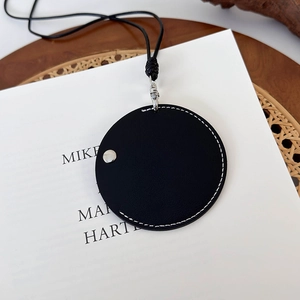 Détail d'un mini porte-monnaie en cuir noir avec coutures blanches et bouton pression argenté