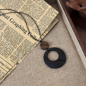 Gros plan d'un pendentif anneau noir en résine avec connecteur en bois naturel