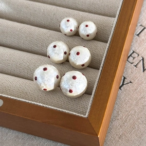 Detail of French vintage cotton pearls with red polka dots on a beige jewelry tray