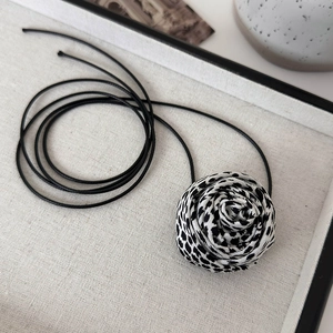 Detailed view of the leopard print fabric rose flower on a long black cord choker necklace