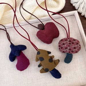 Detailed view of forest-style handmade fabric fruit pendants with rustic cord necklaces