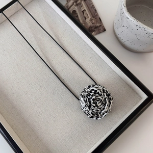 Detailed view of leopard print fabric rose pendant with a black long adjustable rope cord