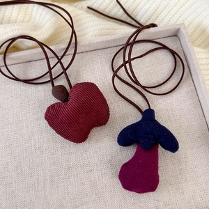 Handmade corduroy fruit and mushroom necklaces for children shown on a knit sweater