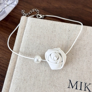 Close-up of a white leather rose and pearl on a minimalist snake chain choker