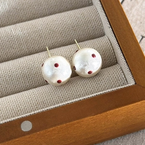 Close-up of red polka dot cotton pearl studs in a linen-lined wooden jewelry box