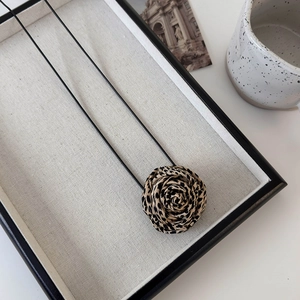 Close-up of leopard print fabric rose flower pendant on a black string choker necklace