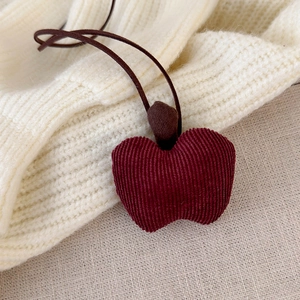 Detailed view of the dark red corduroy apple pendant with textured fabric and top cord