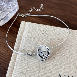 Detail view of a matte rose pendant and polished bead on a silver snake chain choker