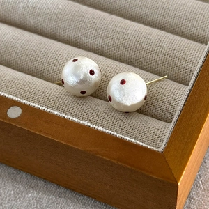 Macro shot of red polka dot cotton pearl studs on a beige velvet jewelry box display