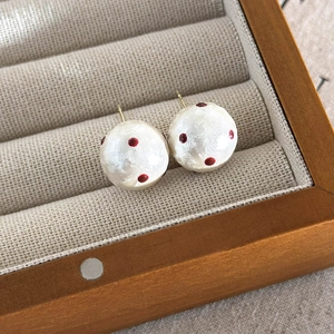 Detail of red polka dot cotton pearl studs on a velvet jewelry box slot