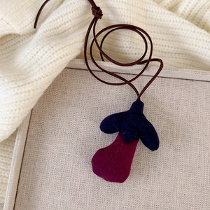 Detail of handmade cotton-stuffed eggplant pendant necklace for kids' autumn fashion
