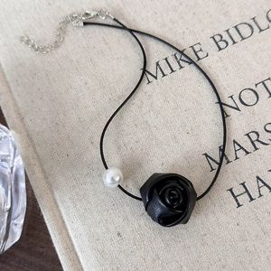 Detailed macro of a black leather rose and white faux pearl on a minimalist choker necklace