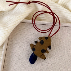 Detail of forest-style handmade stuffed fabric pendant with polka dots on a knit background