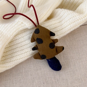 Close-up of handmade fabric tree pendant with blue dots and red string on knit background