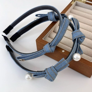 Detailed view of denim bow headband featuring white pearl accents and non-slip inner grip