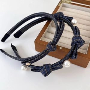 Detail of denim bow headband with white pearl accents and non-slip inner teeth design