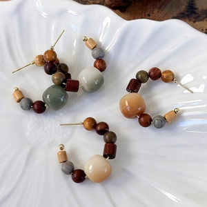 Detail of three pairs of ethnic beaded hoop earrings made of wood and resin on ceramic tray
