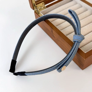 Detail of blue denim bow headband showing non-slip teeth and golden button accent