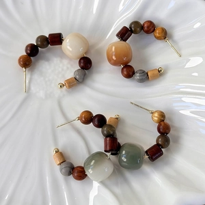Detail of vintage beaded hoop earrings with wood and marble beads on a ceramic plate