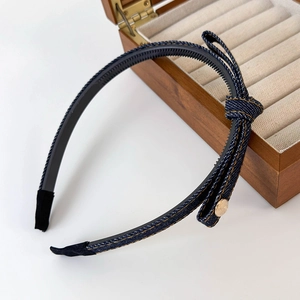 Detail of denim bow headband showing vintage gold button and black non-slip inner teeth