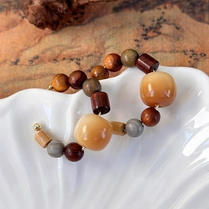 Close-up of bohemian sandalwood C-shaped hoop earrings with colorful beaded accents