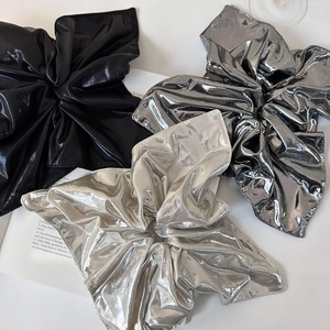Detailed view of oversized metallic scrunchies in silver, black and grey tones