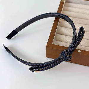 Detail of denim blue headband with yellow stitching, side bow and gold buckle detail