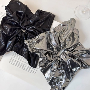 Oversized satin scrunchies in silver and black colors displayed on a stylish magazine