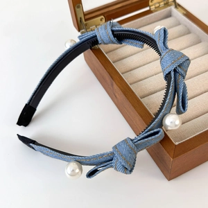 Detail of denim bow headband featuring white pearls and black non-slip teeth grip
