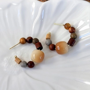Detail view of handmade vintage C-shaped earrings with sandalwood and amber resin beads