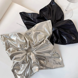 Close-up of metallic silver and black oversized scrunchies on a white magazine background