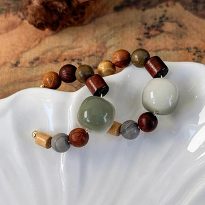 Macro detail of bohemian C-ring earrings with sandalwood beads and ceramic stones