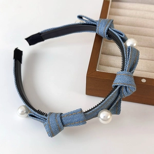 Detail of light blue denim headband with three bow accents and four white pearls
