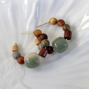 Detailed view of ethnic C-hoop earrings with sandalwood, grey stone and jade-like beads
