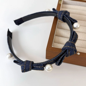 Detail of denim bow headband featuring white faux pearls and yellow contrast stitching