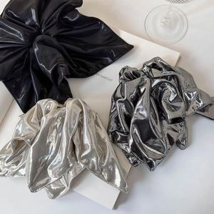 Close-up of oversized metallic scrunchies in silver and grey on minimalist background