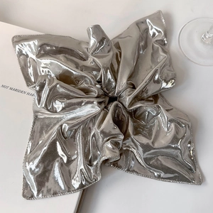 Macro shot of high-shine silver scrunchie with metallic pleated texture for hair