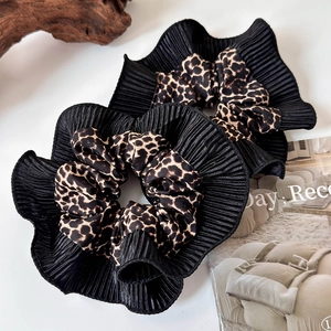 Detail of leopard print scrunchie with black pleated lace on a wooden tray decor