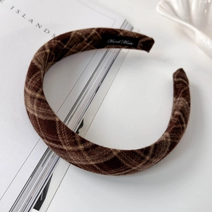 Detail showing handcrafted brown plaid fabric headband with a woven Hand Made label inside