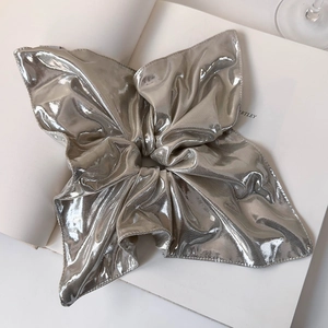 Detail of silver metallic scrunchie with bow design and reflective fabric texture