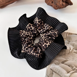 Detail of a large scrunchie featuring black pleated fabric and leopard print pattern
