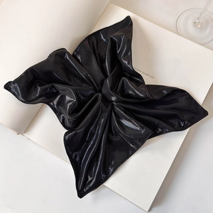 Macro view of a large black metallic bow hair clip with glossy finish on a book