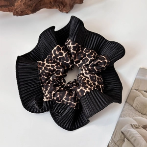 Detail of the leopard print and black pleated fabric texture on a large hair scrunchie
