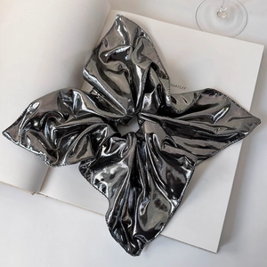 Macro shot of high-shine silver metallic fabric scrunchie with exaggerated pleats
