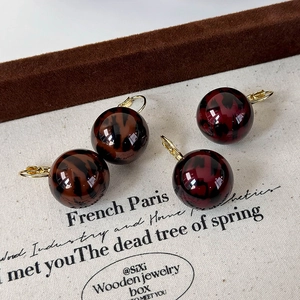 Elegant leopard print ball earrings with gold lever-back hooks in brown and deep red colors