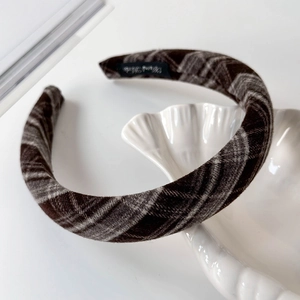 Detailed view of the brown plaid thick headband with textured wool fabric on shell plate