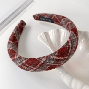 Detailed close-up of thick red and grey plaid fabric headband on a white shell tray