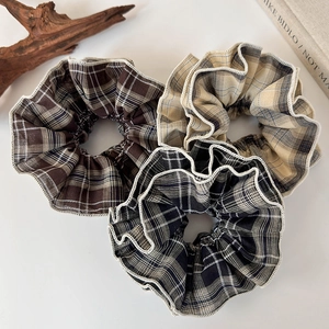 Flat lay detail of vintage plaid scrunchies in brown, beige, and black checkered patterns