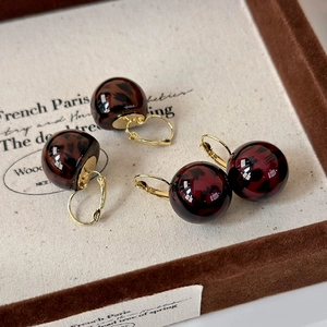 Macro shot of leopard print ball earrings in amber brown and burgundy resin finishes
