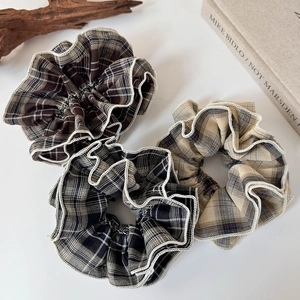 Detailed view of three vintage plaid scrunchies with white lace edges on a white table